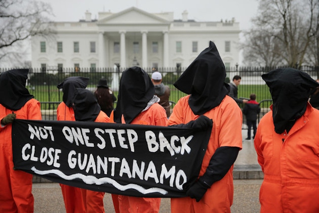 WASHINGTON, DC - JANUARY 08: Demonstrators with the group Witness Against Torture dress in orange jumpsuits and wear black hoods while demanding that U.S. President Barack Obama close the military prison in Guantanamo, Cuba, outside the White House January 8, 2016 in Washington, DC. There are still 104 terrorism detainees from Afghanistan, Yemen, Saudi Arabia, Pakistan and other countries being held at the maximum security prison. (Photo by Chip Somodevilla/Getty Images)